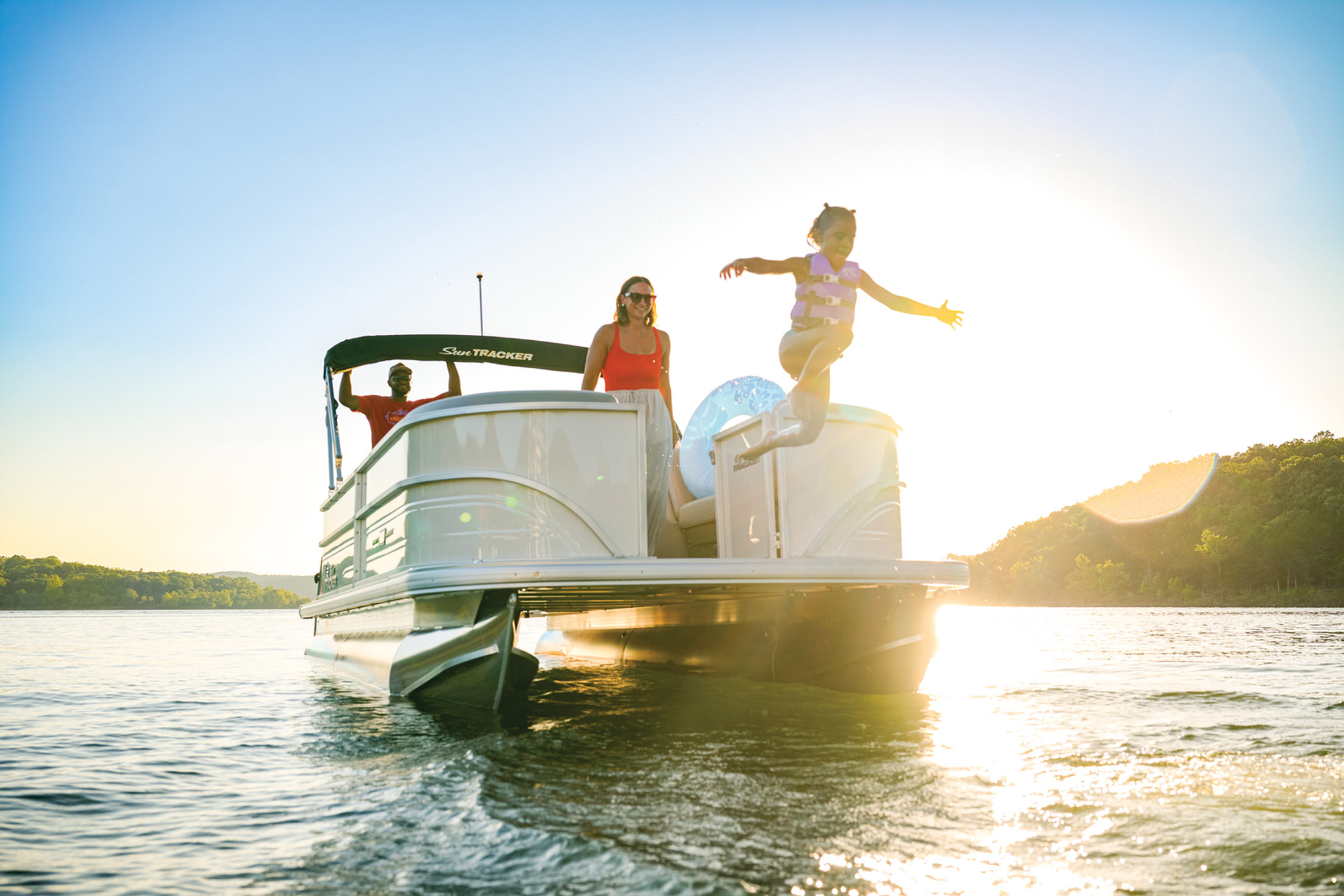 Family jumping off a pontoon into lake